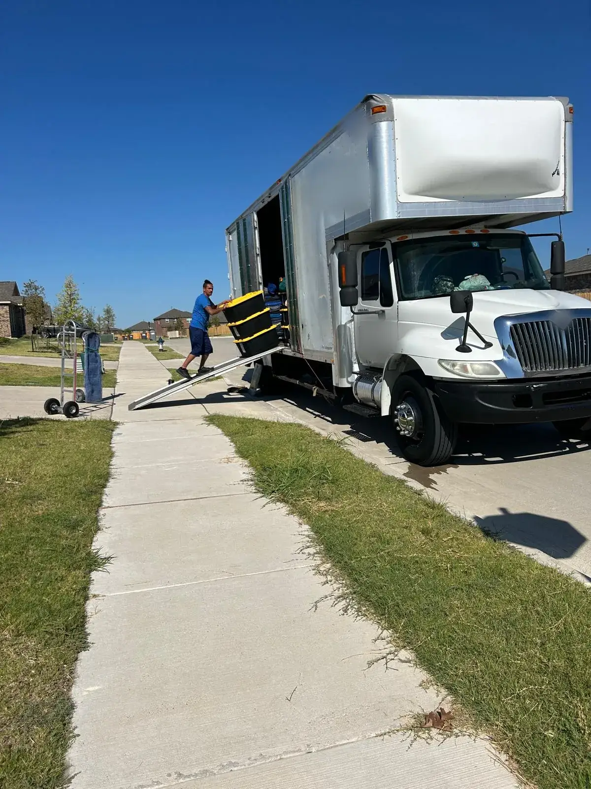 Champion Moving crew member carrying stacked totes up the ramp into a box truck