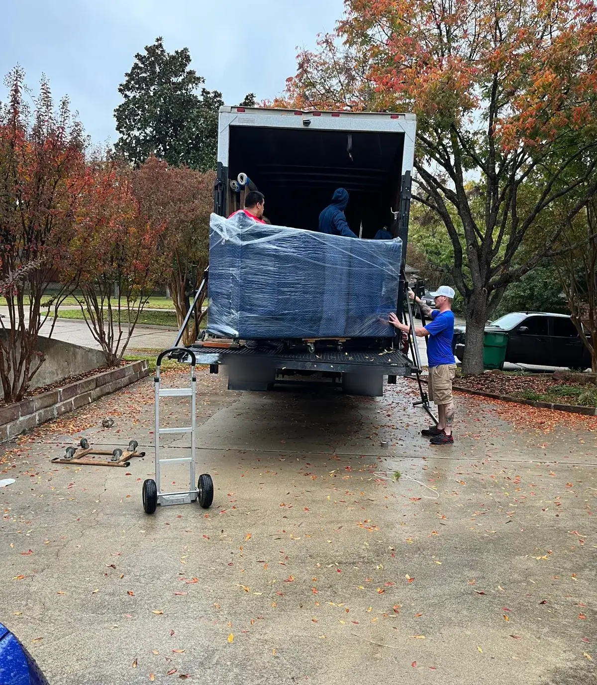 Champion Moving crew loading blanket-wrapped furniture onto a truck liftgate