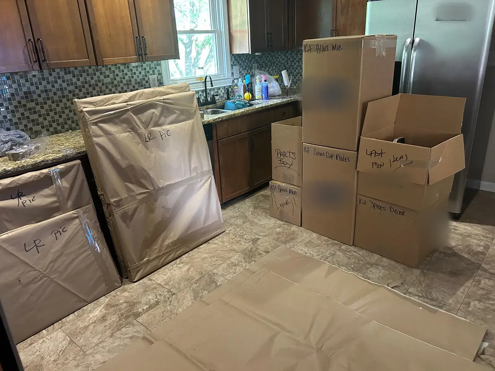 Kitchen packed into labelled boxes with paper-wrapped pictures and floor protection